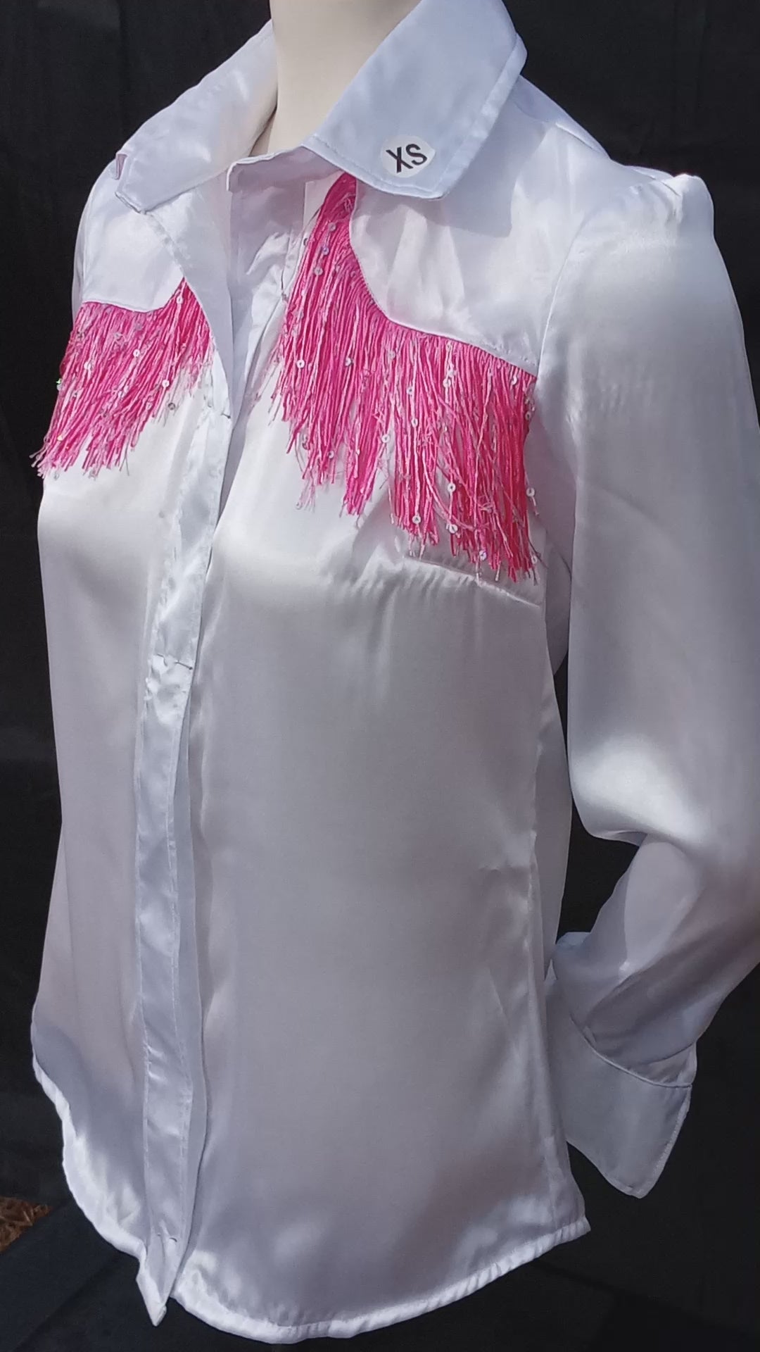 This video shows a 360 view of my handmade white with pink sparkly fringe western shirt. It highlights the way the light reflects off of satin fabric as well as the pink sparkly fringe accent. My customers have the option of buttons or pearl snaps. My shirts are available in sizes XS-5XL.  C Boondocks Treasures Boutique 2025
